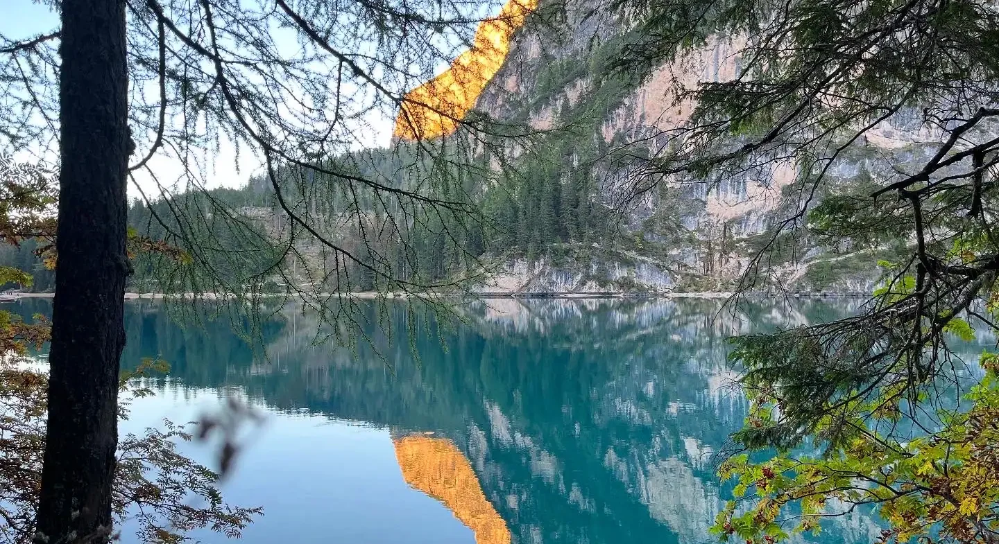 Serene mountain lake with reflections of cliffs and lush forest, perfect for outdoor adventures and nature photography.